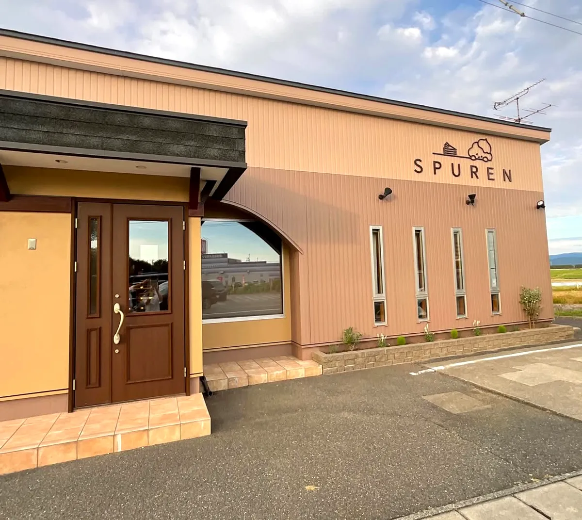 SPURENの店舗外観。木製ドアのエントランスとロゴサイン